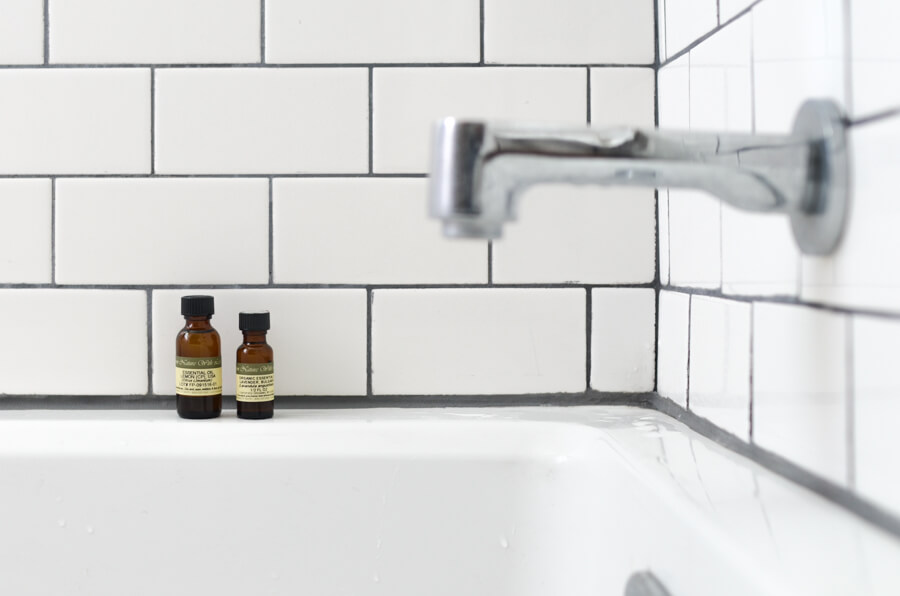 two oil bottles next to a bathtub