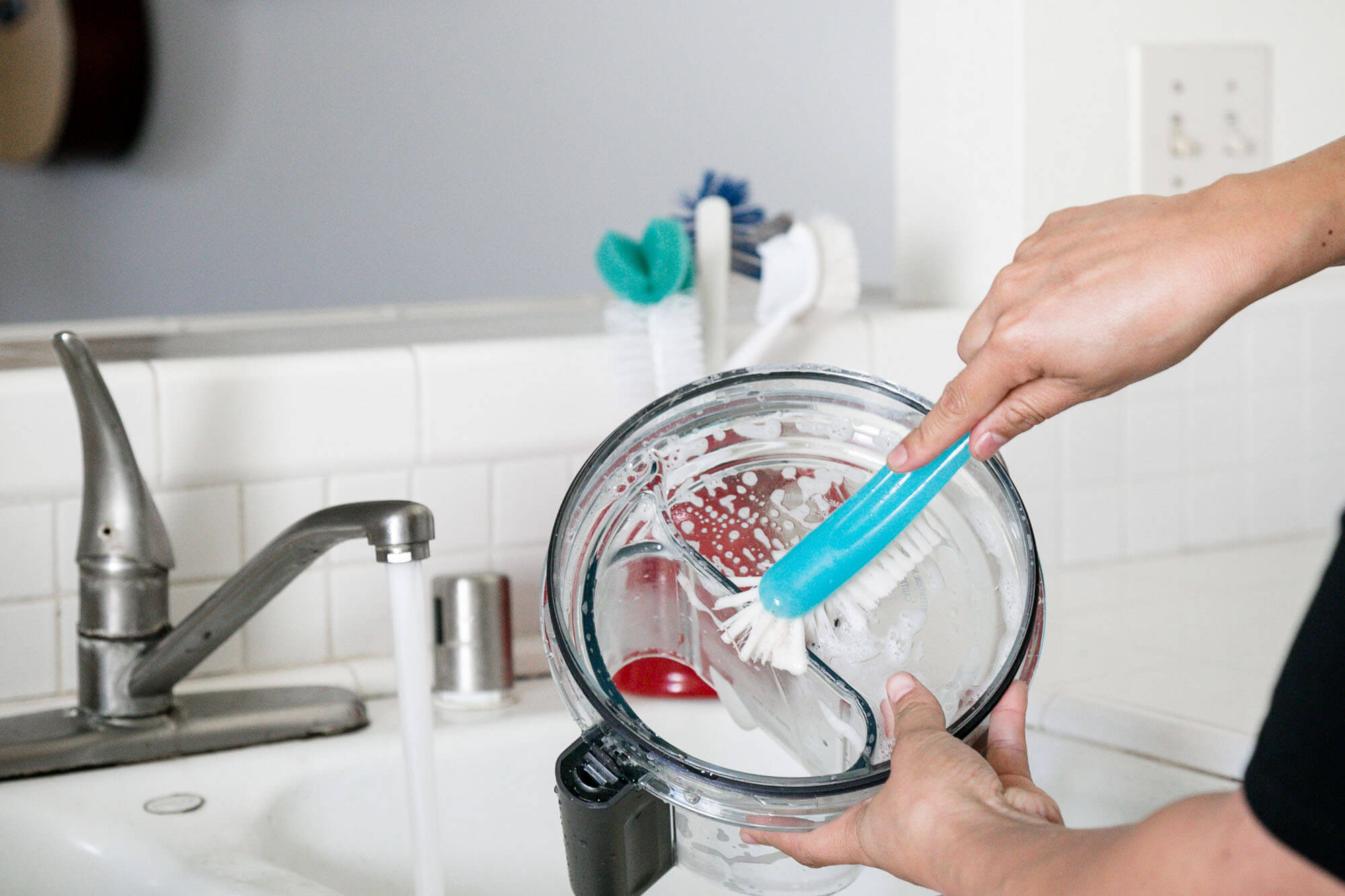 hand-washing a food processor lid in the sink
