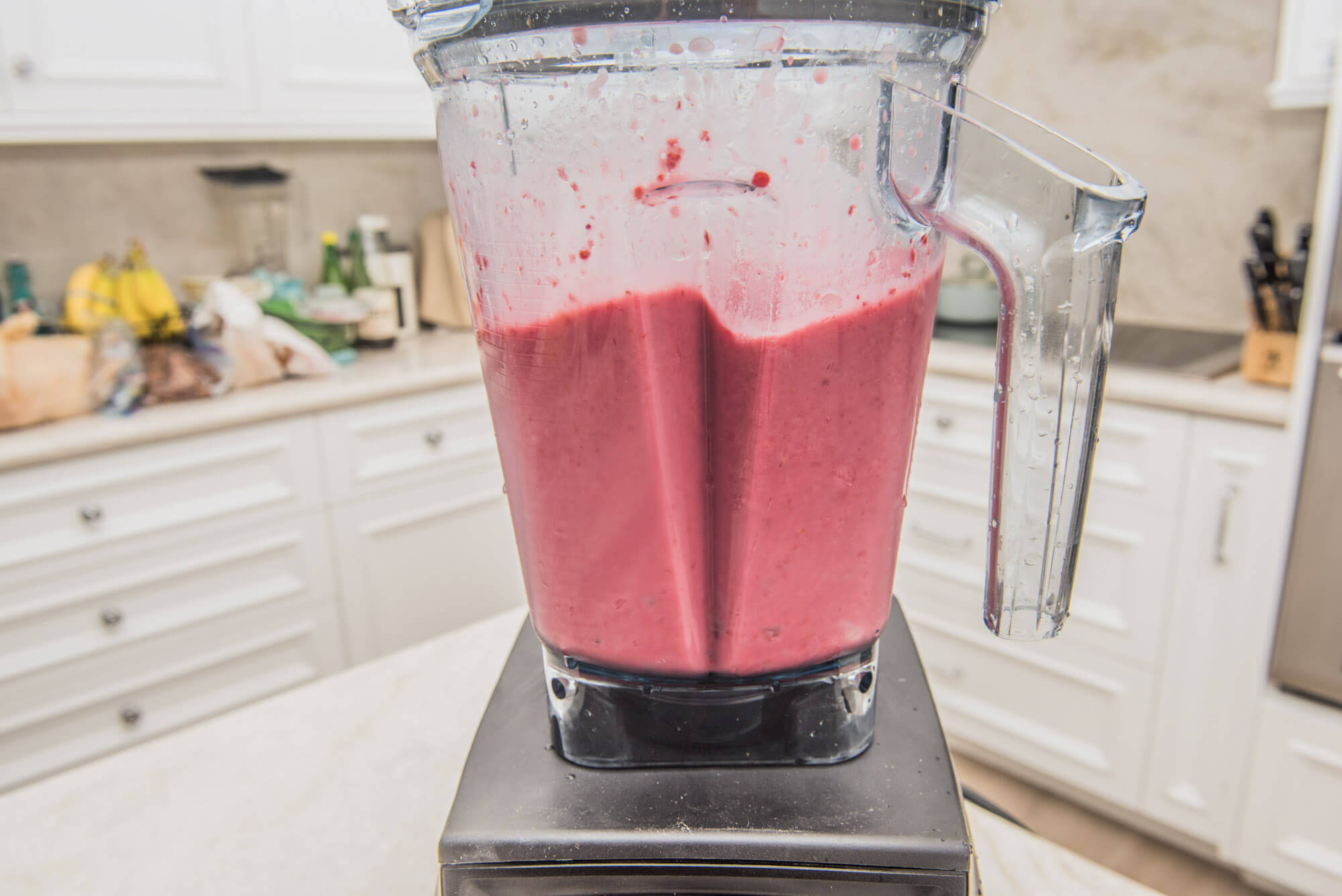 Blending a strawberry smoothie in kitchen. 