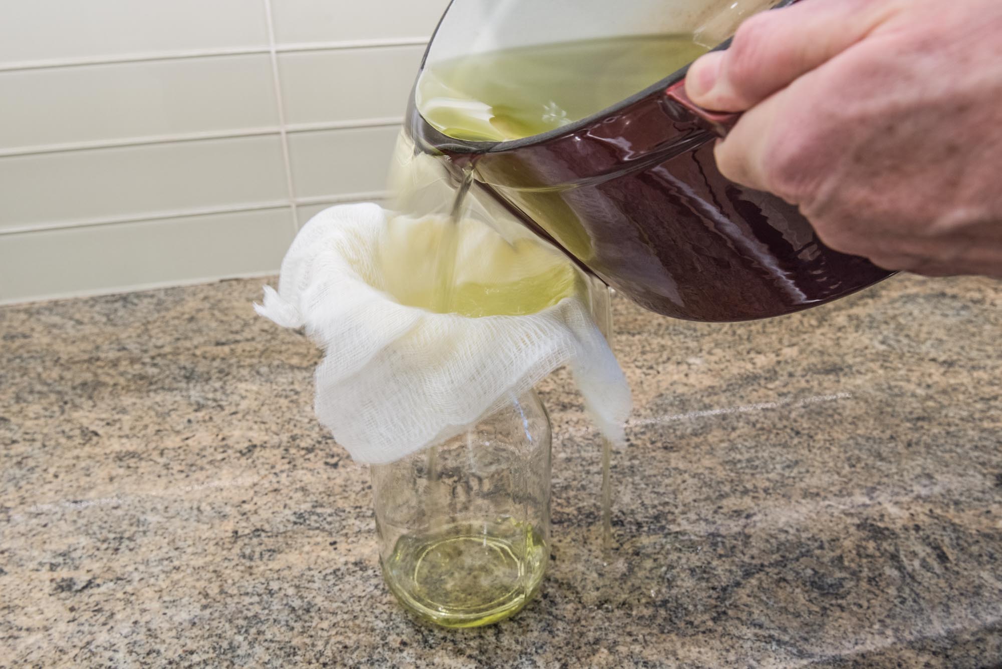 pouring out oil to strain and store in a glass jar